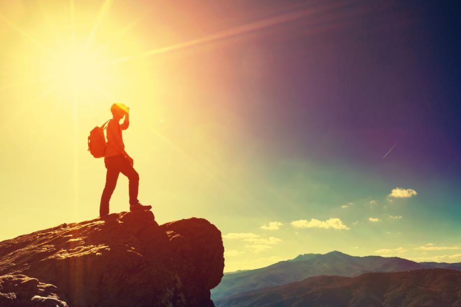 A man standing on a rock, staring out into the distance