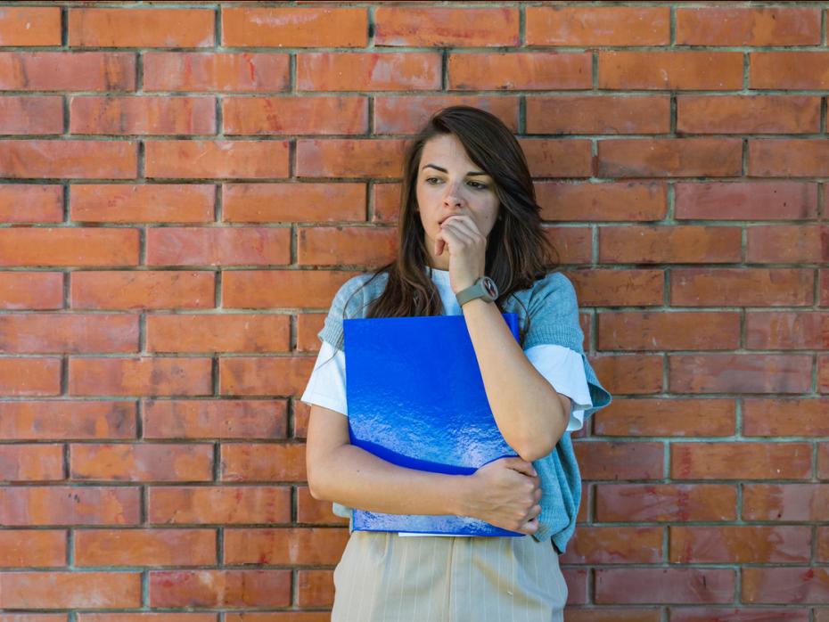 A student standing outside campus thinking