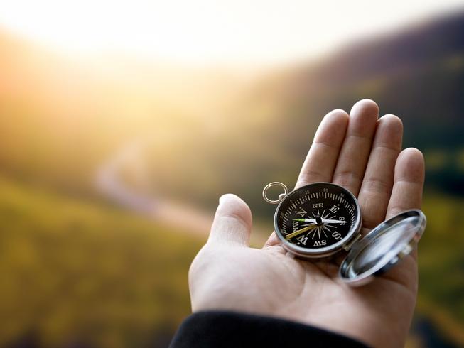 A hand holds a compass