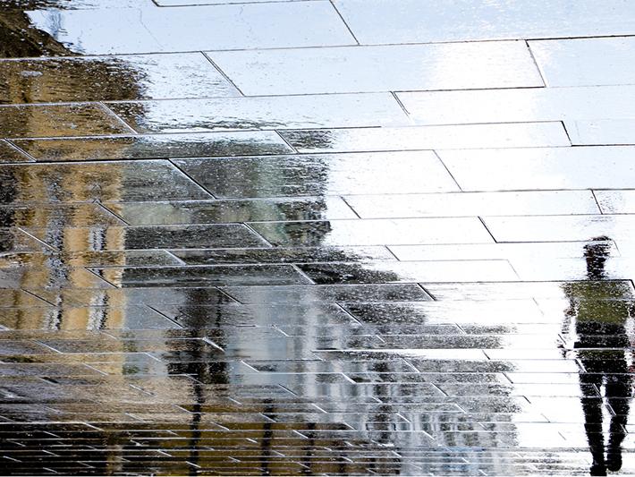Distorted reflection of a man walking in the street