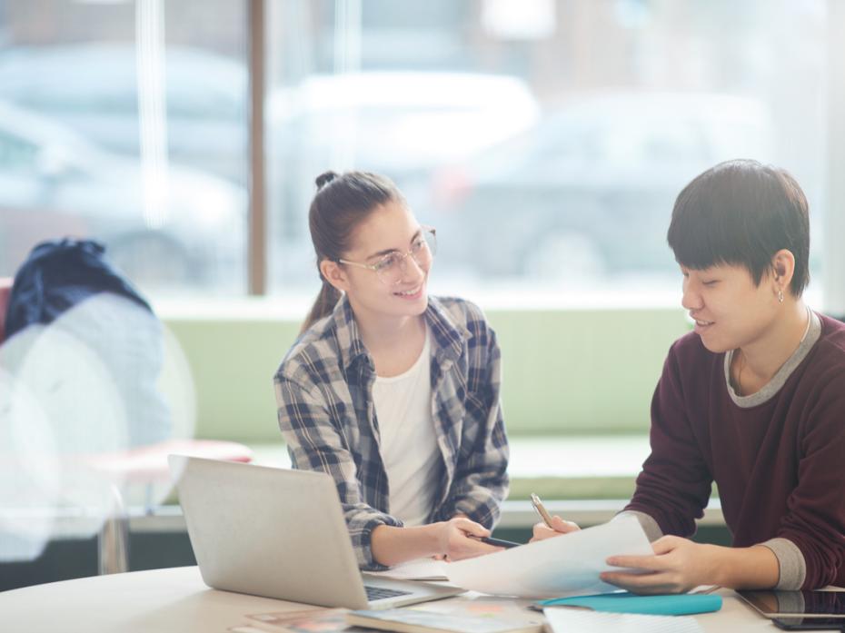 Two students sitting at a table discussing a GenAI prompt