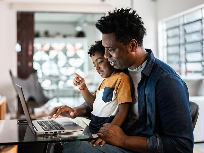 Man with child on his lap working at computer