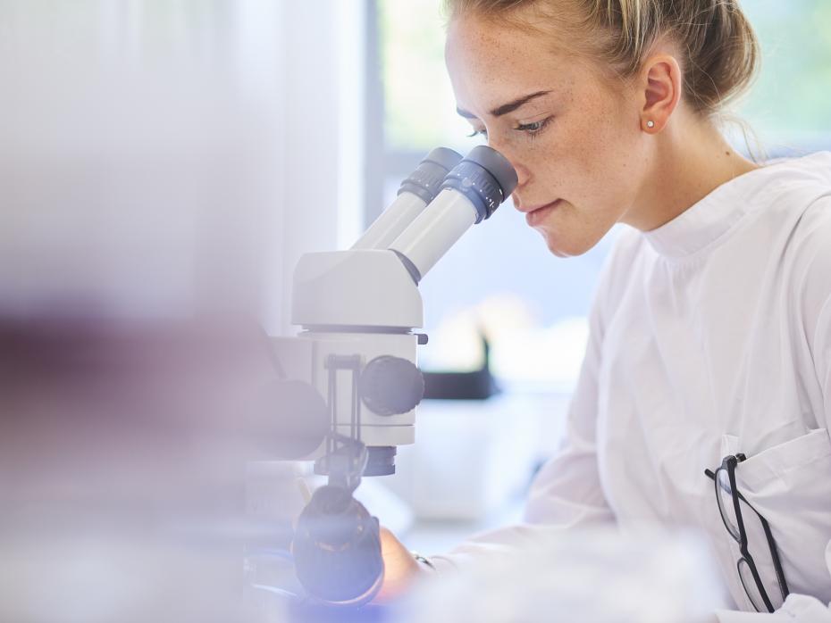 Female student looking through a microscope