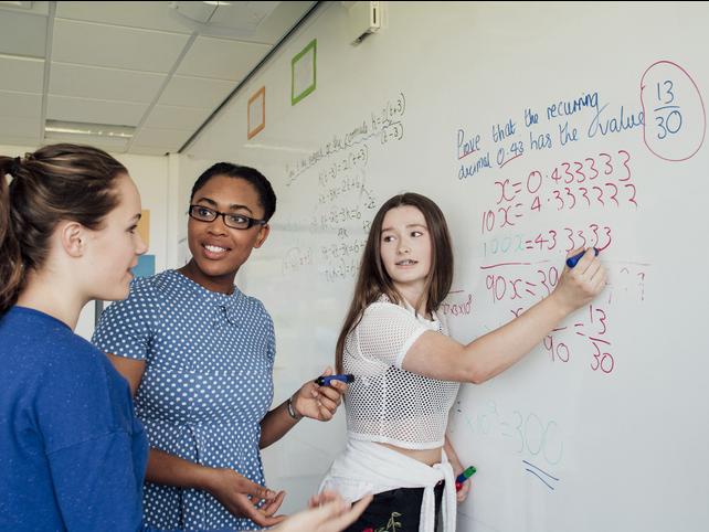 Secondary students solving a maths problem on a whiteboard