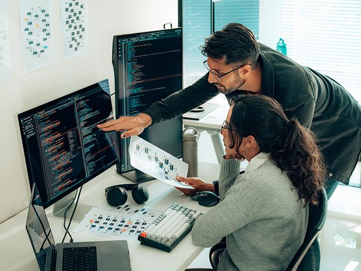 Two people looking at code on a computer screen