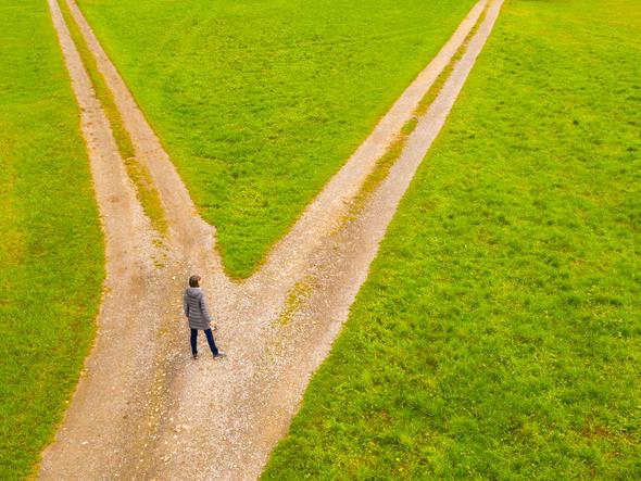 A woman stands at the crossroads of two diverging paths
