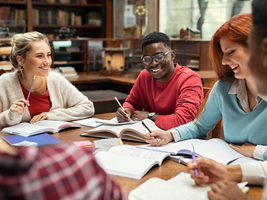 A group of students writing and talking together