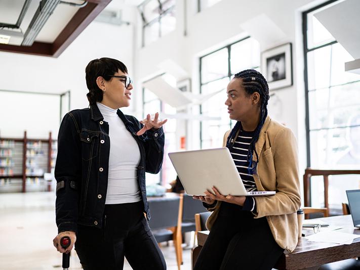 Transgender disabled woman talking to a researcher with a laptop