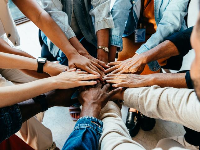 Team members place their hands in a circle