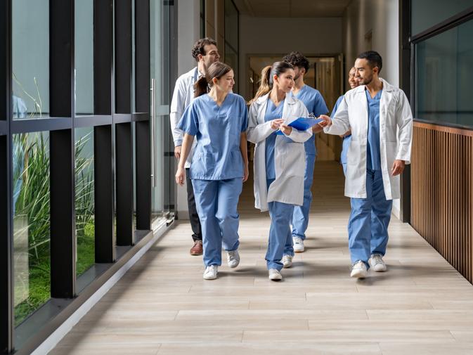 Medical students in scrubs walking down a university building corridor