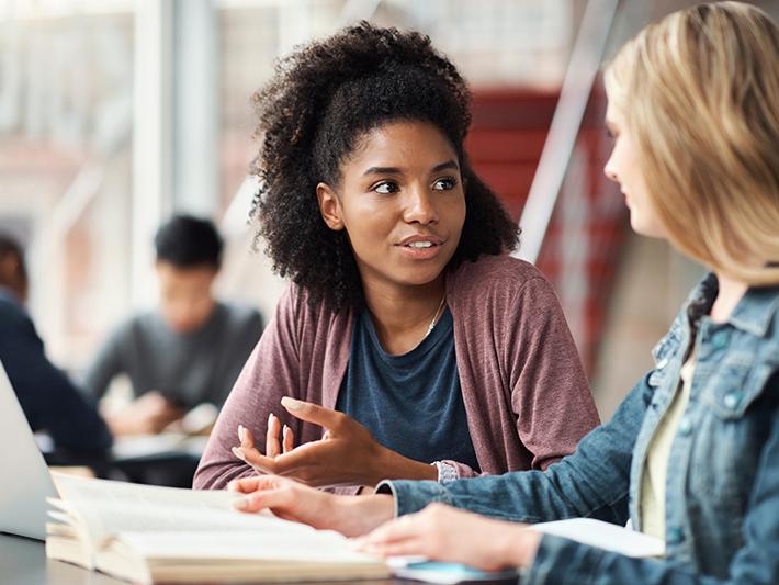 Two female college students discussing something in class