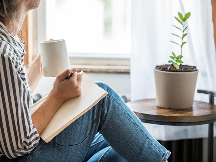 Woman writing in journal by window