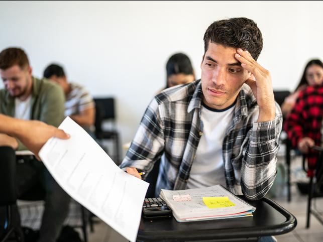 An unenthused student receives a test back in the classroom