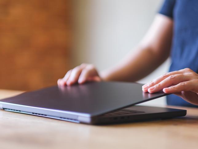 A close-up of a laptop being closed