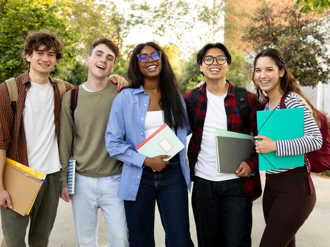A group of smiling students standing outside on university campus grounds