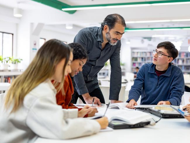 A teacher advises students on their work