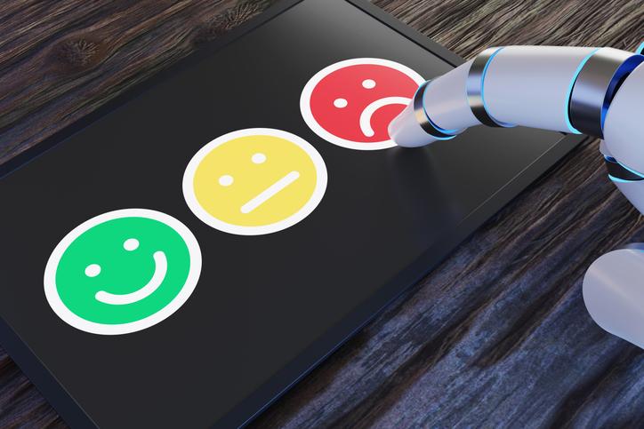 A robot hand takes a survey using emoji faces