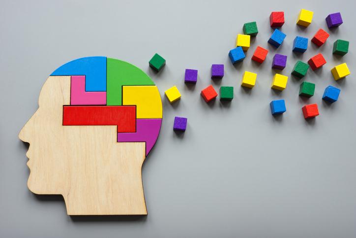 A jigsaw puzzle shaped like a head, brightly coloured blocks emitting from it