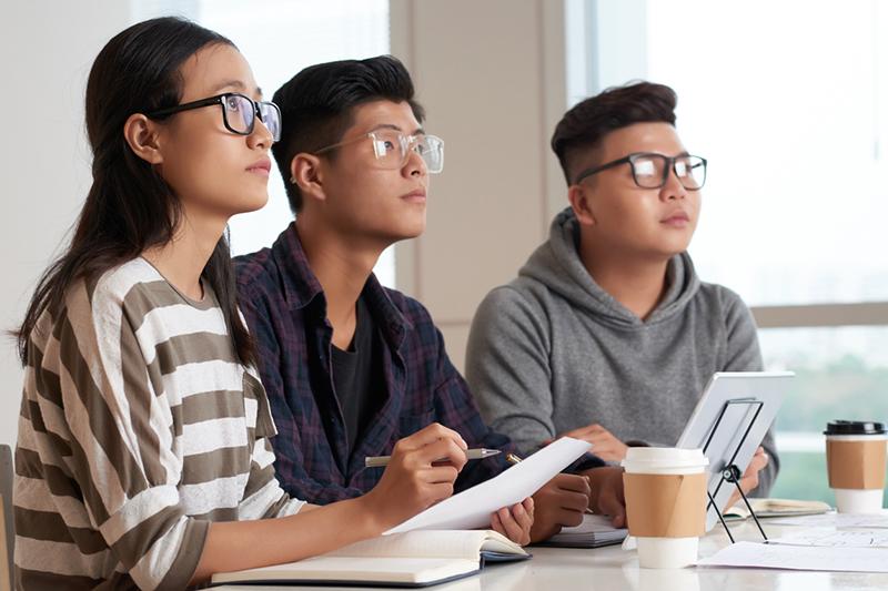 Three Asian university students in a classroom