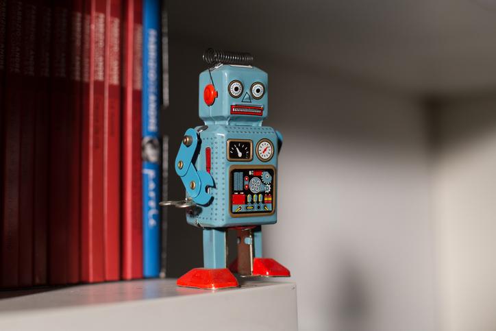 A toy robot stands on a book shelf