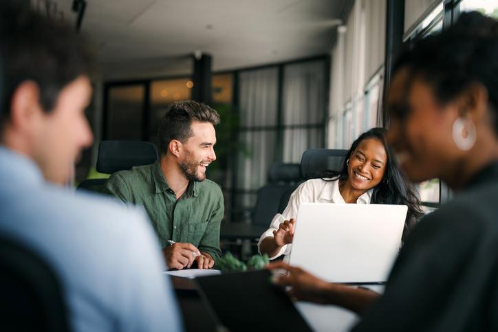 Colleagues laugh together over a laptop