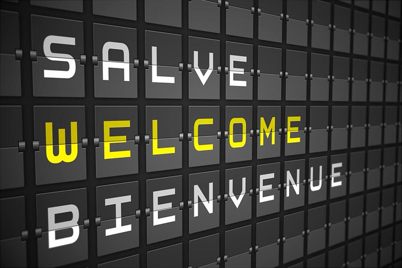 Airport arrival sign with welcome in English, French and Italian