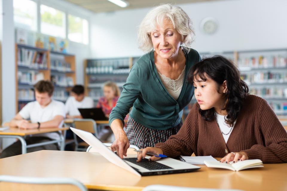 Teacher guiding a student through an exercies on their laptop 