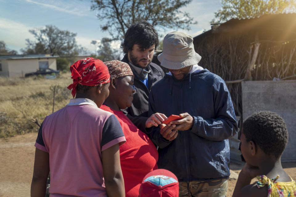 Group of people in Kenya, looking at a mobile phone