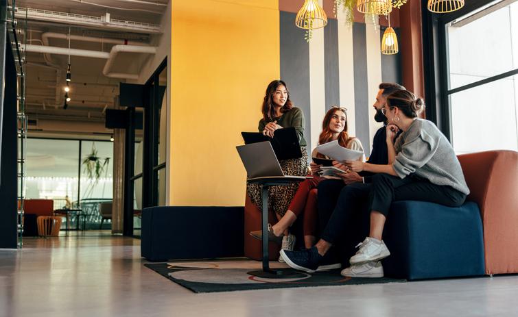 Educators chat on a sofa with a laptop