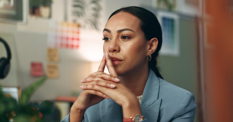 A woman deep in thought sitting at a desk 