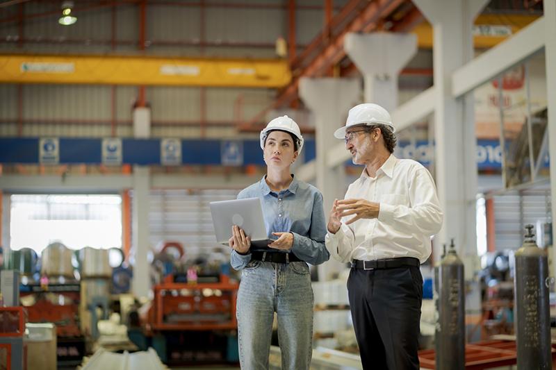 Young female engineer and older male colleague in a factory