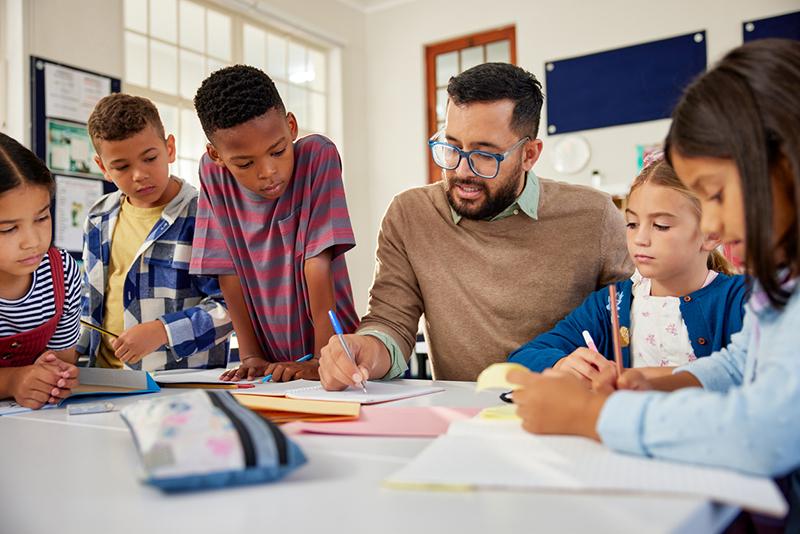 Male teacher working with multiracial primary school class