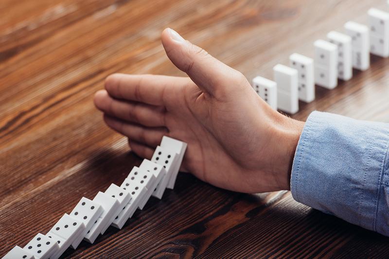 Hand stopping a line of dominoes falling