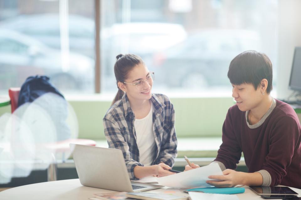 Two students sitting at a table discussing a GenAI prompt