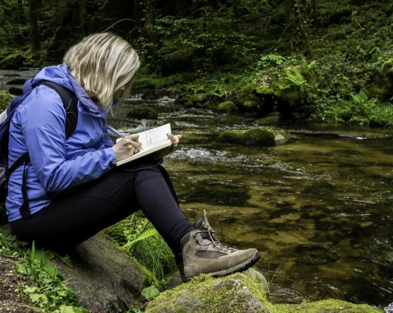 A student on a field trip in the forest taking notes