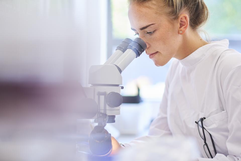 Female student looking through a microscope