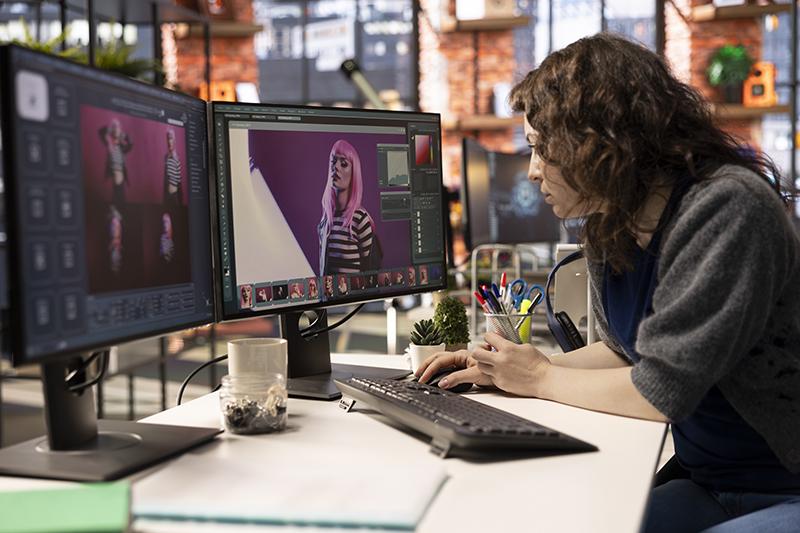 Female designer working with AI chat bot and an editing software - stock photo
