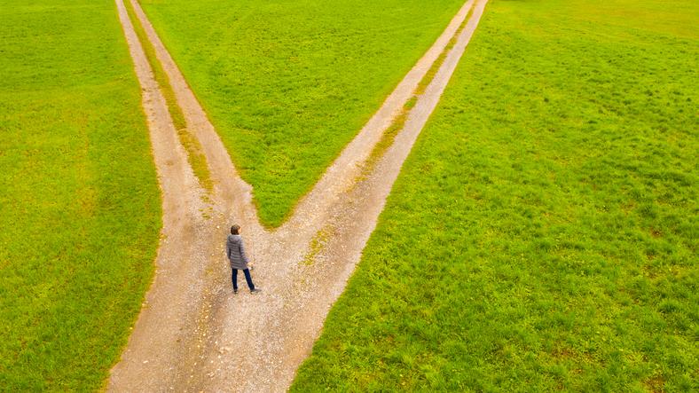 A woman stands at the crossroads of two diverging paths