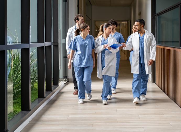 Medical students in scrubs walking down a university building corridor 