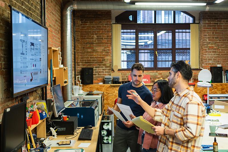 Three people working in an industrial design studio