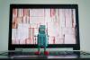 A toy robot observes a laptop screen, filled with books