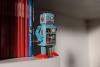 A toy robot stands on a book shelf