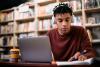Young black student in headphones at laptop
