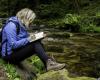 A student on a field trip in the forest taking notes
